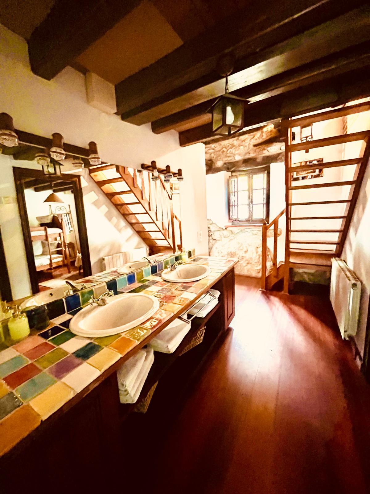 Baño con doble lavabo y azulejos artesanales de colores en casa rural de Castañeda