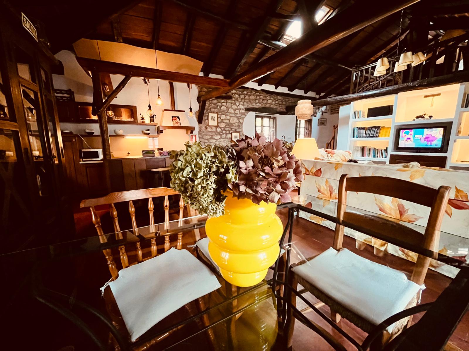 Comedor abierto a la cocina rústica con vigas de madera — alojamiento rural HdeC en Cantabria