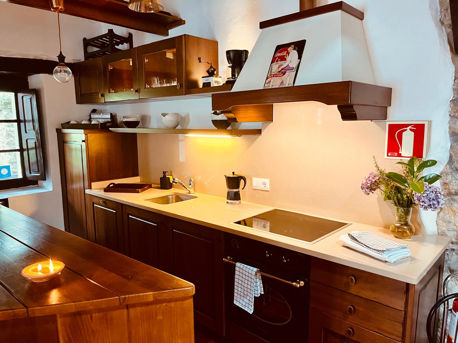 Cocina equipada con vitrocerámica y campana de madera en casa rural de Puente Viesgo