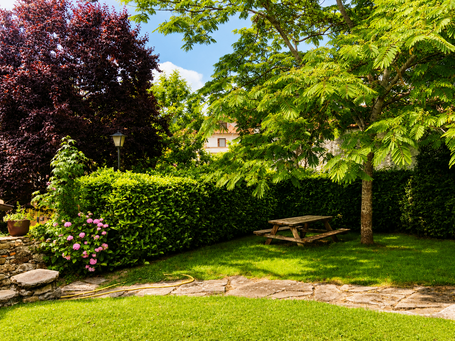 Jardín con cerezo y mesa de picnic en casa rural de Puente Viesgo, Cantabria