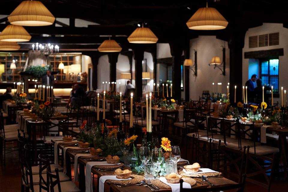 Comedor con mesas vestidas, velas y girasoles en la Hostería de Castañeda